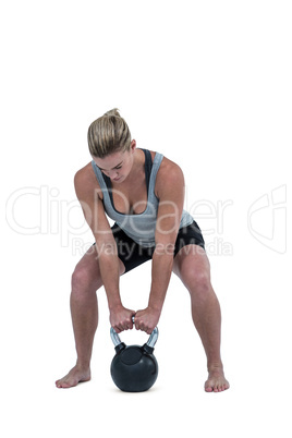 Serious muscular woman lifting kettlebell