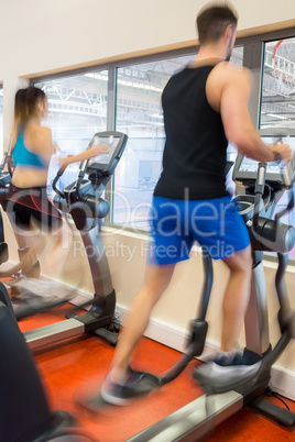 Man and woman using ellipitical machines