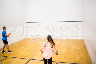 Competitive couple playing squash together