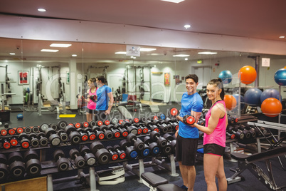 Woman lifting dumbbells with her trainer