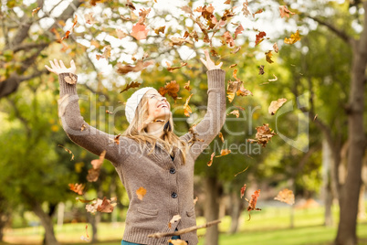 Smiling woman throwing leaves around
