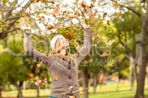 Smiling woman throwing leaves around