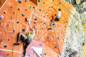 Fit couple rock climbing indoors