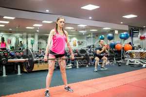 Fit woman lifting heavy barbell in weights room