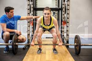 Woman lifting barbell and weights with trainer watching