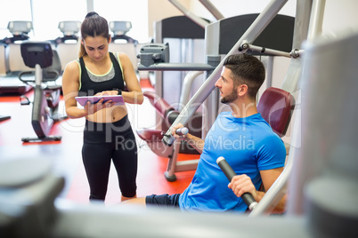 Trainer working with athlete at weights machine