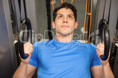 Man pulling himself up with the rings in hand