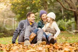 Smiling young family sitting in leaves