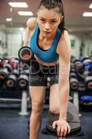 Focused woman lifting dumbbell weight in hand