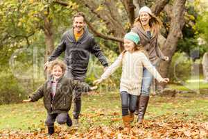Smiling young family running into leaves