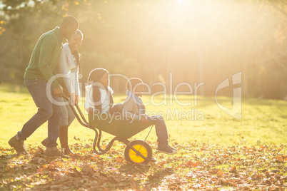 Young parents holding their children in a wheelbarrow