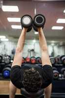 Man lifting dumbbell weights while lying down