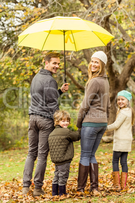 Rear view of young smiling family under umbrella