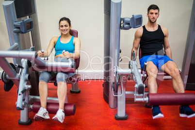 Man and woman both using weights machine