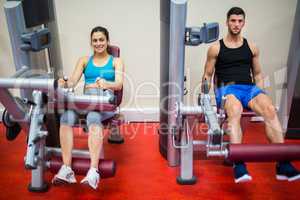 Man and woman both using weights machine