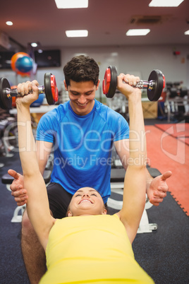 Woman lifting dumbbells with her trainer