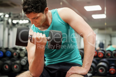 Man lifting dumbbell weight while sitting