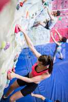 Fit woman rock climbing indoors