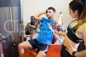 Concentrating man using weights machine with trainer