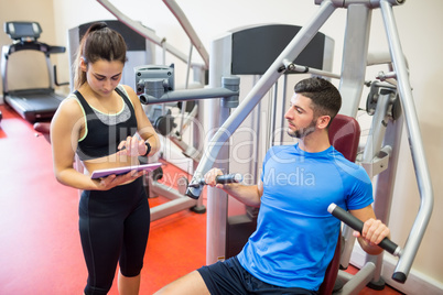 Trainer working with athlete at weights machine