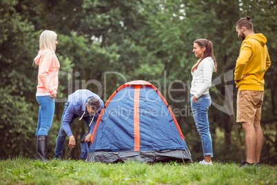 Happy friends setting up their tent