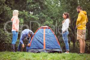 Happy friends setting up their tent