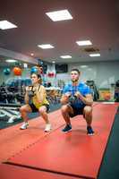 Couple crouching down while holding kettlebells