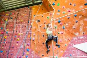 Fit blonde rock climbing indoors