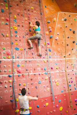 Woman climbing up rock wall