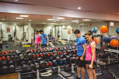 Woman lifting dumbbells with her trainer