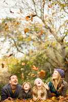 Smiling young family throwing leaves around
