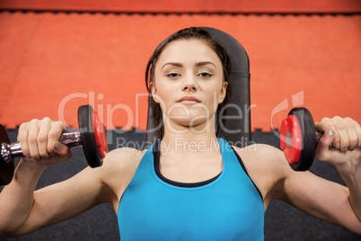 Focused woman lifting dumbbells while lying down