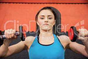 Focused woman lifting dumbbells while lying down