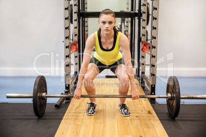 Concentrated woman about to lift a barbell and weights