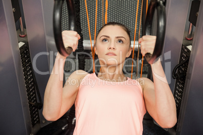 Woman pulling herself up with rings in hand