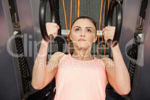 Woman pulling herself up with rings in hand