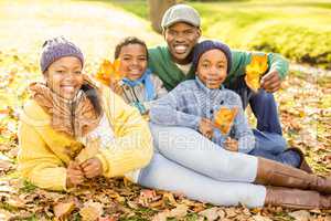 Young smiling family sitting in leaves
