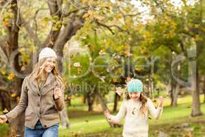 Mother and daughter throwing leaves around
