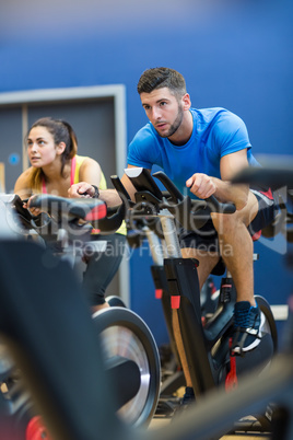 Focused couple using exercise bikes