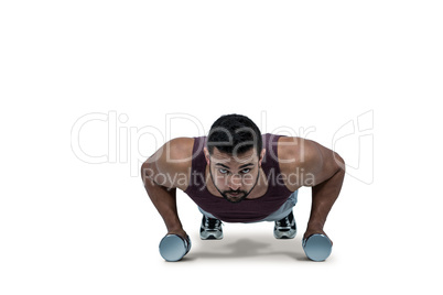 Muscular man doing push ups with dumbbells