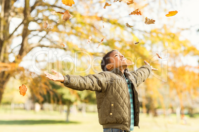 leaves drop onto a little boy with outstretched arms