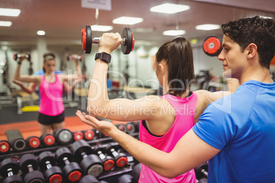 Woman lifting dumbbells with her trainer