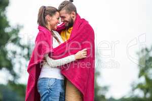 Happy couple hugging under blanket