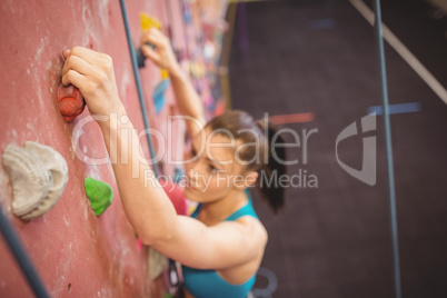 Woman climbing up rock wall