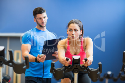 Woman on exercise bike with trainer timing her