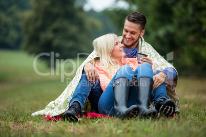 Happy couple sitting under blanket