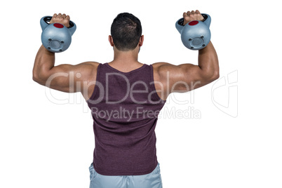 Rear view of a muscular man lifting kettlebells