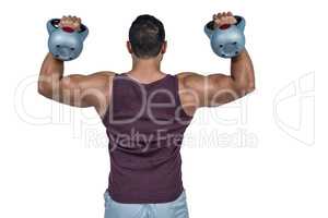 Rear view of a muscular man lifting kettlebells