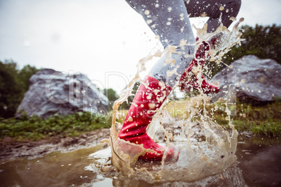 Woman splashing in muddy puddles
