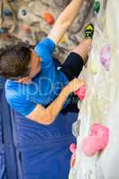 Fit man rock climbing indoors
